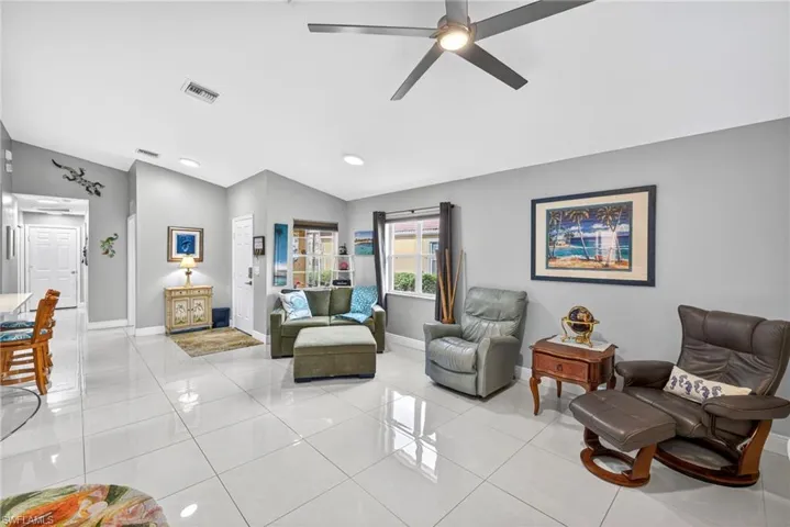Living room with light tile patterned floors, a ceiling fan, and lofted ceiling