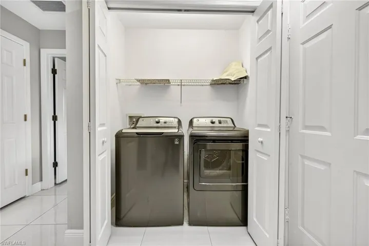 Laundry area featuring light tile patterned floors and separate washer and dryer