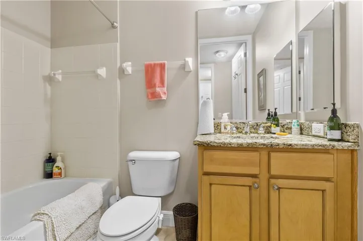 Full bathroom with tiled shower / bath, vanity, and toilet