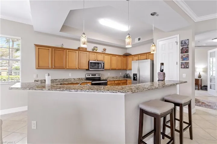 Kitchen with decorative light fixtures, appliances with stainless steel finishes, and light tile flooring
