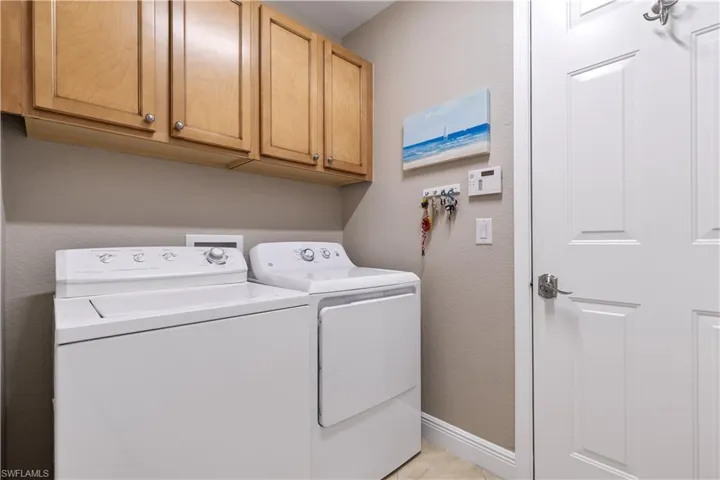 Laundry room with washer and dryer, cabinets, washer hookup, and light tile floors
