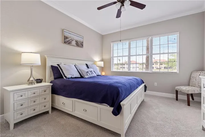 Bedroom featuring light colored carpet, ornamental molding, and ceiling fan