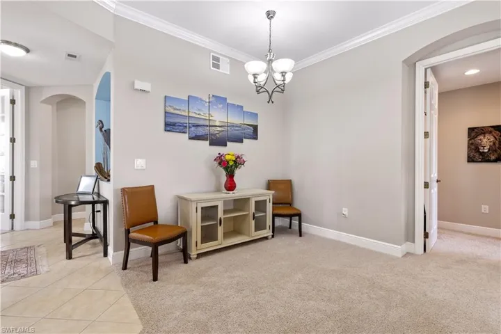 Living area with a notable chandelier, light carpet, and crown molding