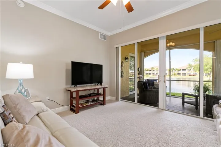 Carpeted living room featuring a water view, ceiling fan, and crown molding