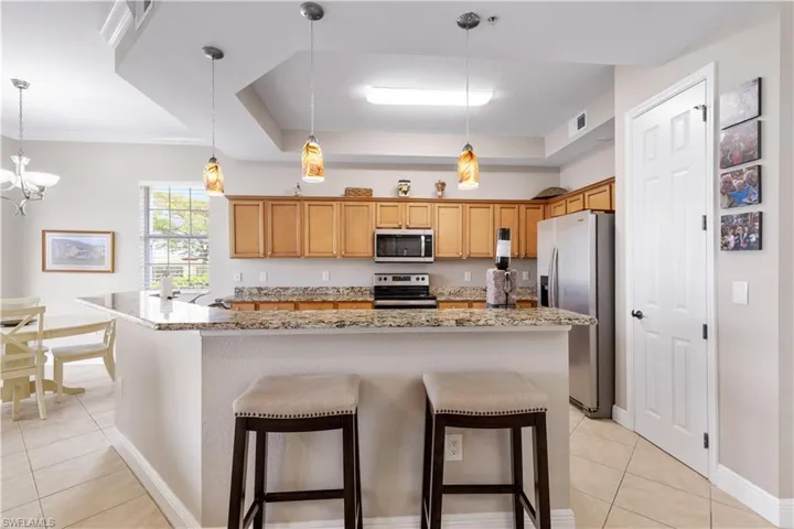 Kitchen featuring a raised ceiling, stainless steel appliances, and decorative light fixtures