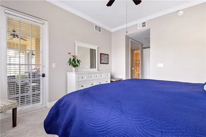 Bedroom with light colored carpet, ceiling fan, and crown molding