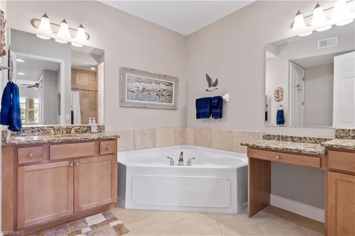 Bathroom with a washtub, tile flooring, and vanity