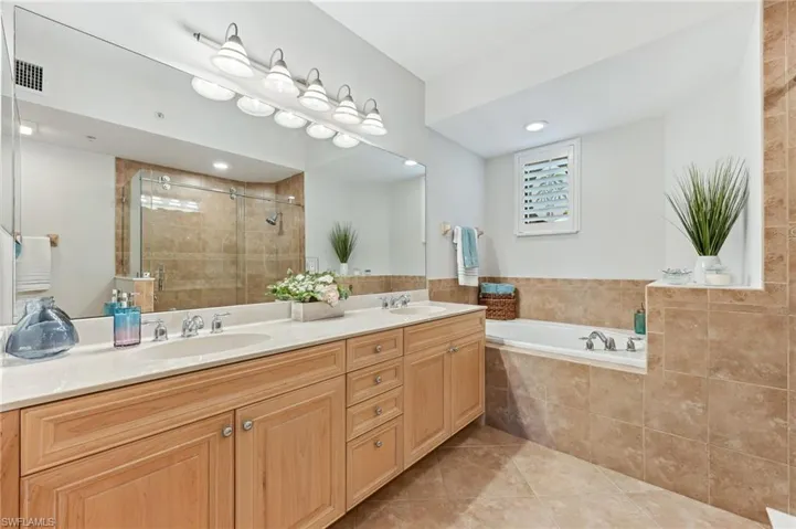Bathroom with tile patterned flooring, double vanity, a shower stall, and a garden tub