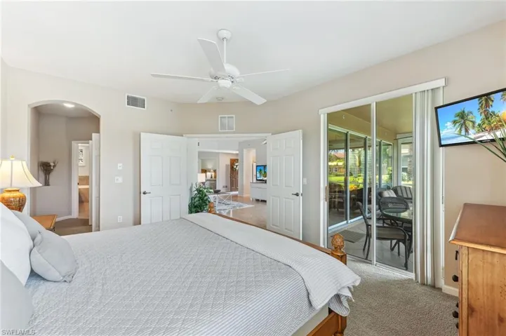 Carpeted bedroom featuring access to exterior, arched walkways, and a ceiling fan