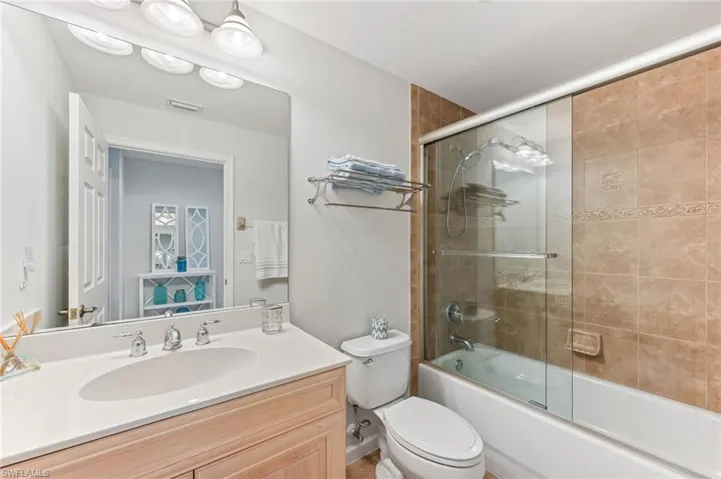 Bathroom featuring vanity and bath / shower combo with glass door