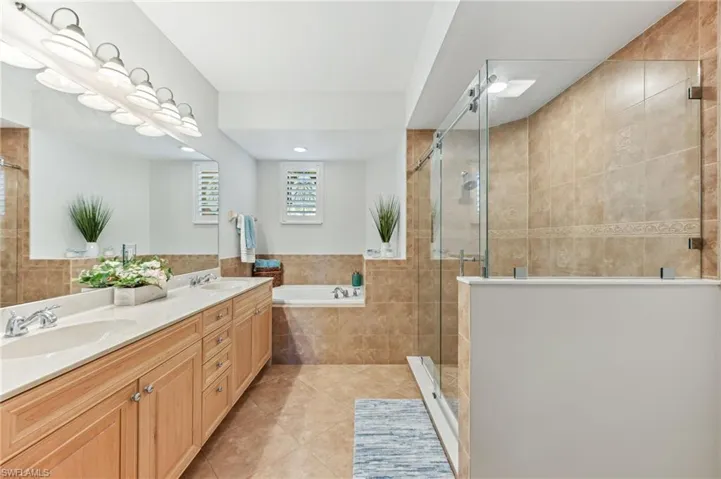 Full bath featuring tile patterned flooring, a garden tub, a shower stall, double vanity, and tile walls