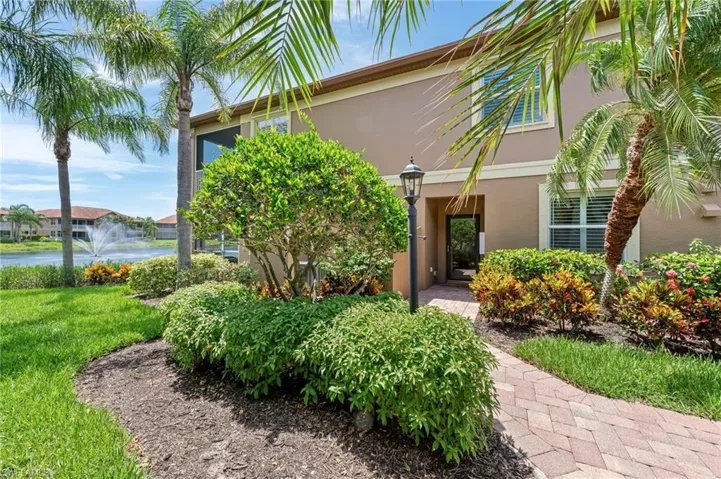 View of exterior entry featuring stucco siding, a lawn, and a water view