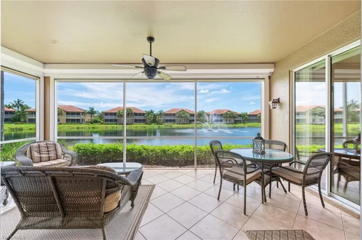 Sunroom / solarium featuring a water view, a ceiling fan, tile patterned flooring, and a residential view