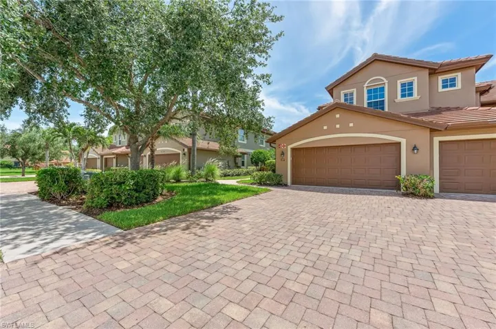 Townhome / multi-family property featuring stucco siding, decorative driveway, a garage, and a tiled roof