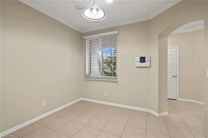 Unfurnished room featuring light tile patterned flooring and crown molding
