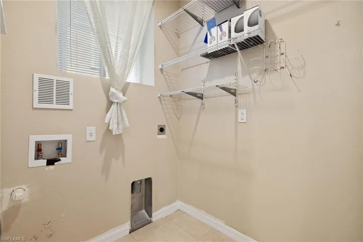 Laundry area with hookup for a washing machine, light tile patterned floors, and hookup for an electric dryer
