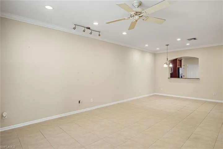Tiled empty room featuring ceiling fan and crown molding