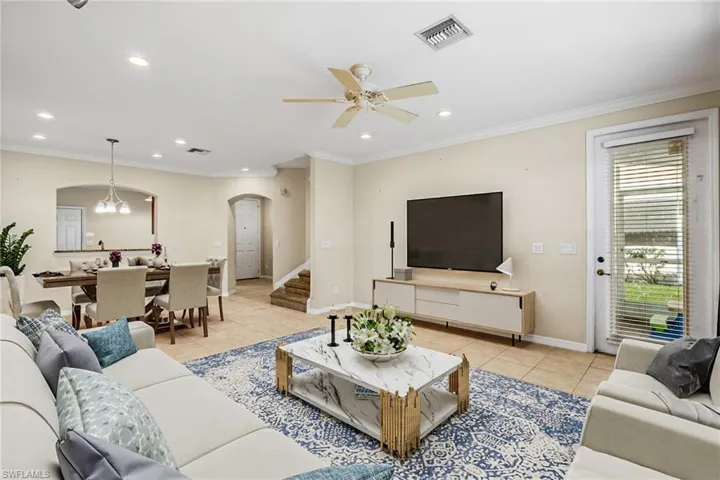 VIRTUALLY STAGED -Tiled living room featuring ceiling fan with notable chandelier and crown molding