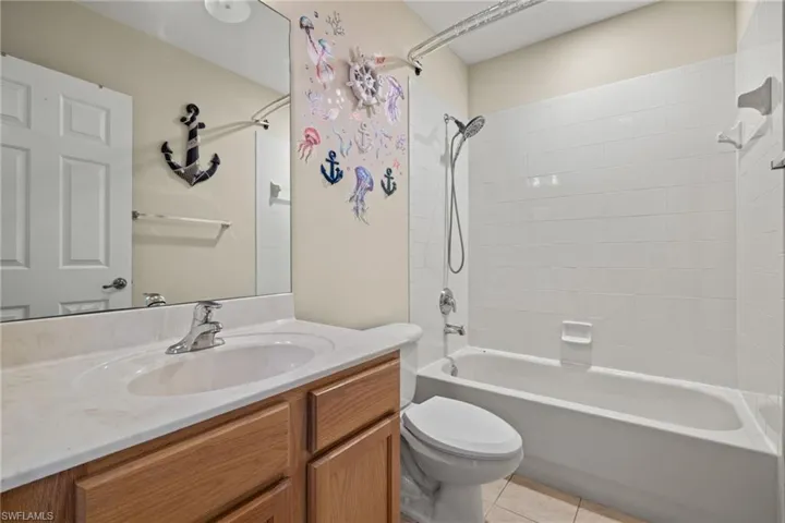 Full bathroom featuring toilet, vanity, tiled shower / bath combo, and tile patterned floors