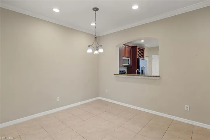 Unfurnished room featuring light tile patterned floors, crown molding, and an inviting chandelier