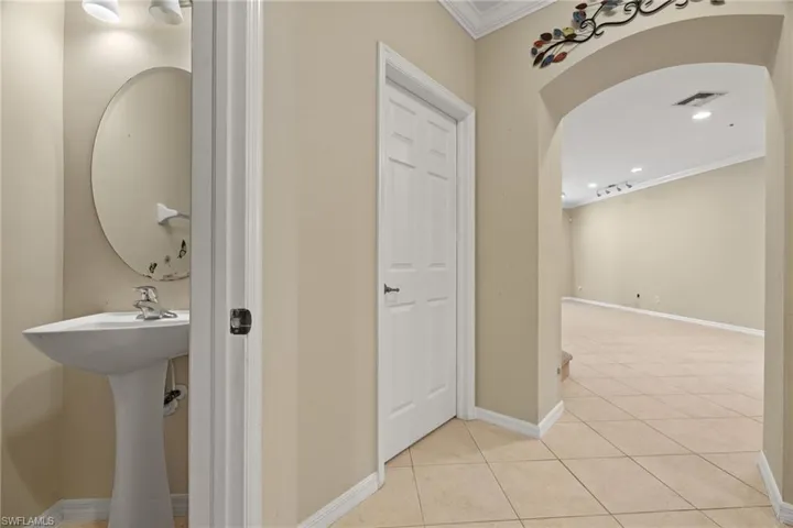 Hall featuring sink, light tile patterned floors, and crown molding