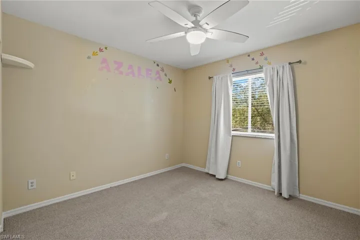 Empty room with ceiling fan and light colored carpet