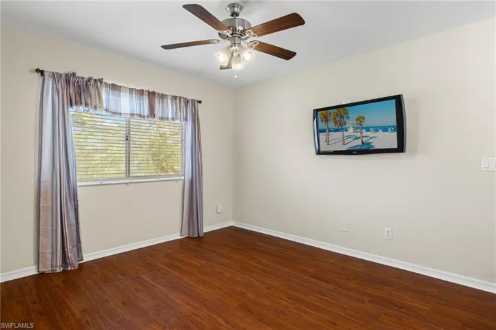 Unfurnished room featuring dark wood-type flooring and ceiling fan