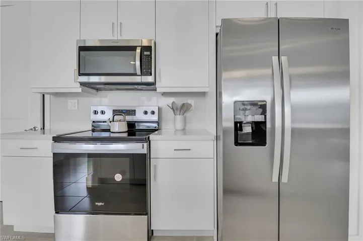 Kitchen featuring stainless steel appliances, light countertops, white cabinets, and modern cabinets