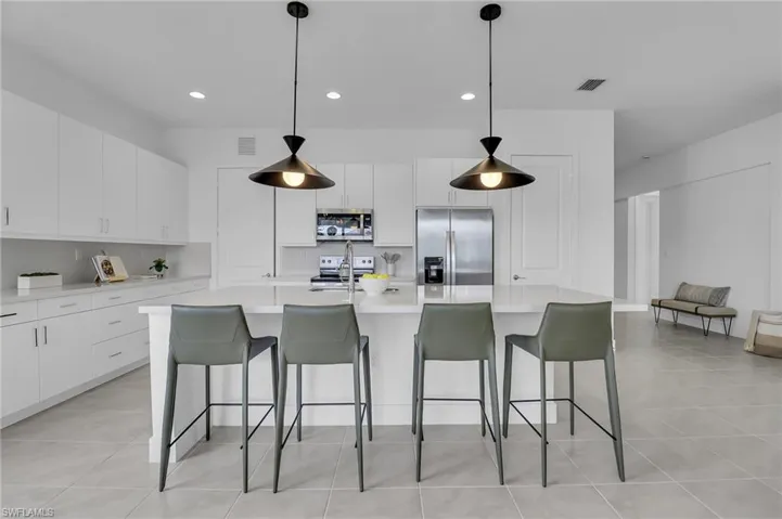 Kitchen with stainless steel appliances, recessed lighting, white cabinetry, a breakfast bar, and light countertops