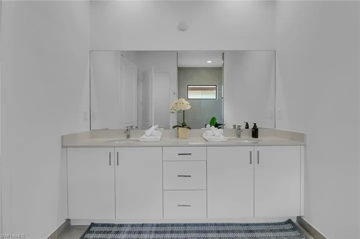 Full bath with double vanity and a tile shower