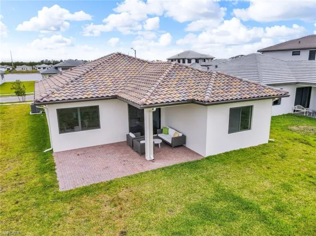 Back of house with stucco siding, outdoor lounge area, a lawn, and a patio area