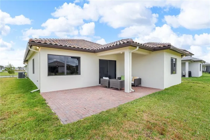 Back of house featuring a patio area, stucco siding, and a lawn