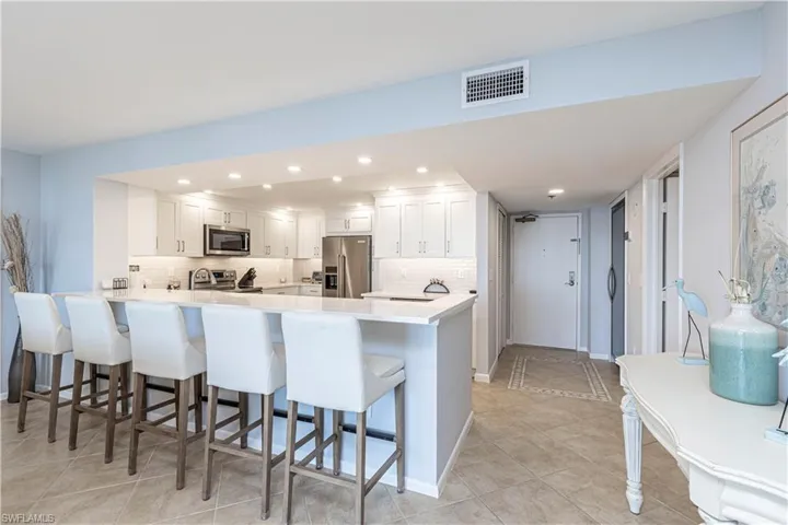 Kitchen with appliances with stainless steel finishes, a peninsula, a kitchen breakfast bar, decorative backsplash, and recessed lighting