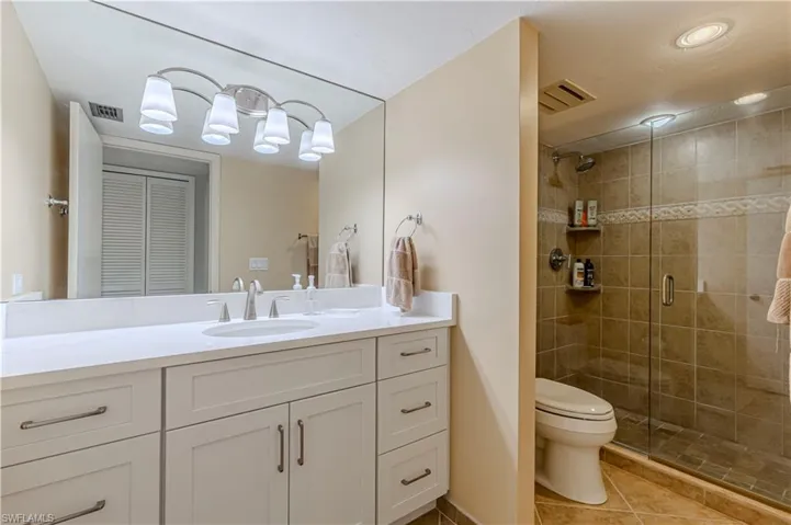 Bathroom featuring toilet, a stall shower, tile patterned floors, and vanity