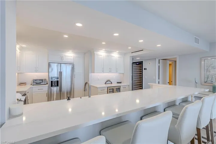 Kitchen with high end refrigerator, wine cooler, a breakfast bar area, backsplash, and recessed lighting