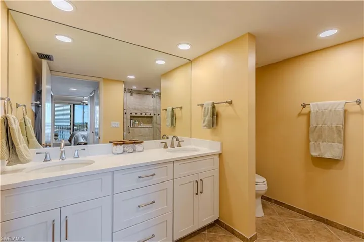 Ensuite bathroom with tile patterned flooring, a stall shower, toilet, recessed lighting, and double vanity