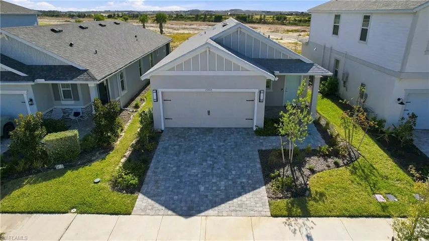 Single-story exterior featuring a gabled roofline, lap siding, a two-car garage, and a decorative paver driveway