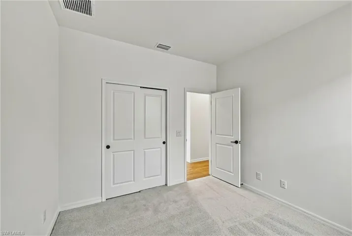 Neutral-toned carpeting, white walls, dual-panel interior doors, and matte black hardware