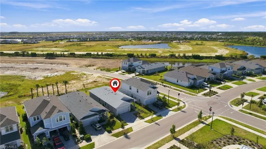 Aerial view of a residential property featuring a paved driveway, a multi-car garage, and roof-mounted solar panels