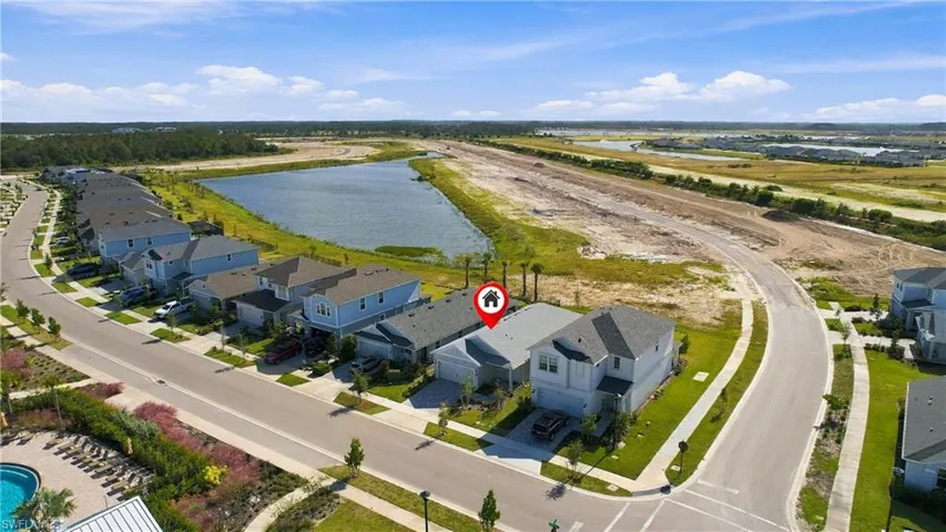 Aerial perspective of a multi-story residence featuring a shingled roof, a paved driveway, and a front-facing garage