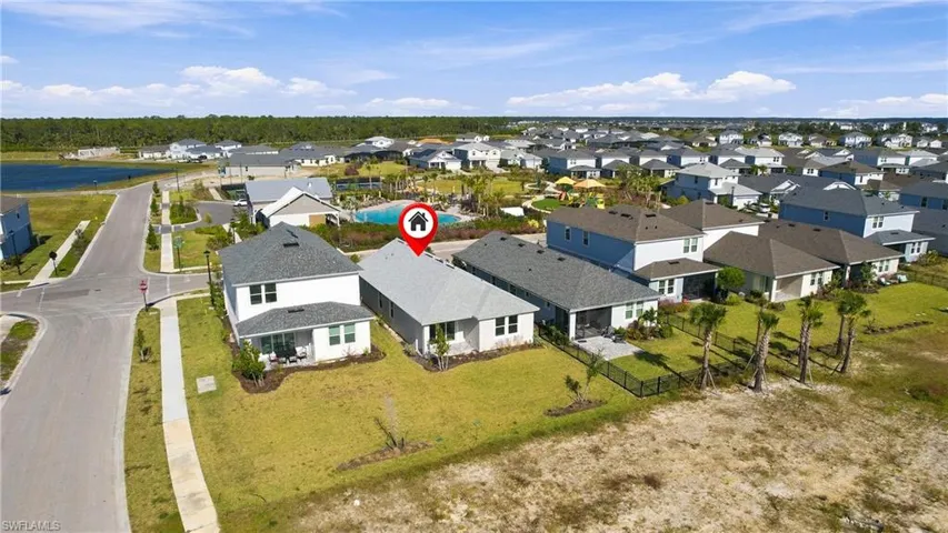 Aerial perspective of a single-story residence featuring a shingled roof, stucco exterior, corner lot positioning, and proximity to neighborhood water features