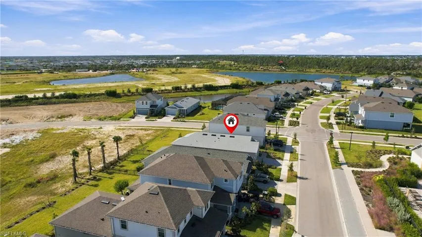 Aerial perspective of a multi-story residence featuring a shingled roof, attached two-car garage, and proximity to community water features