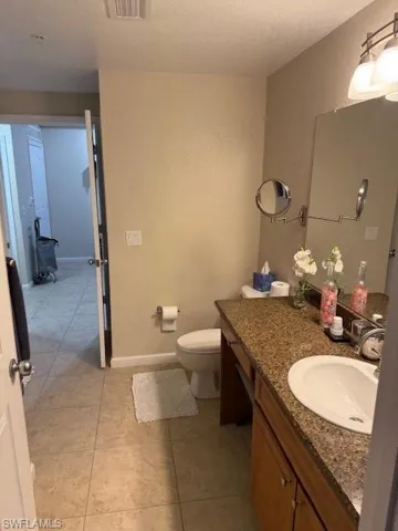 Bathroom featuring vanity, toilet, tile patterned flooring, and a textured ceiling