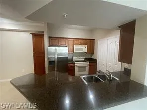 Kitchen with sink, white appliances, and kitchen peninsula