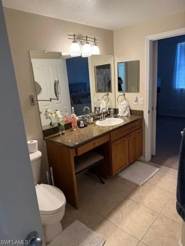 Bathroom with vanity, tile patterned flooring, a textured ceiling, and toilet