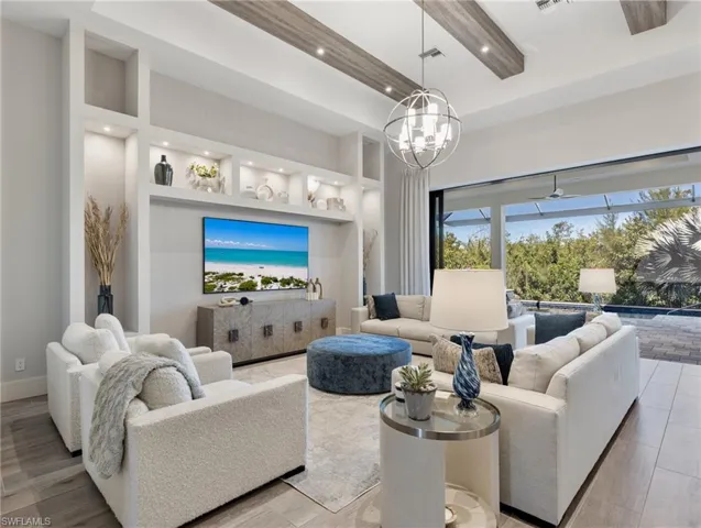 Living area with built in features, wood finished floors, recessed lighting, a towering ceiling, and a chandelier