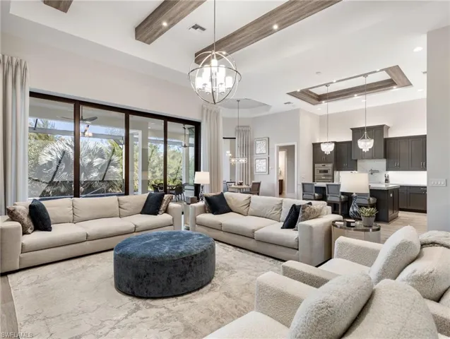 Living area with a tray ceiling, a high ceiling, recessed lighting, and a chandelier