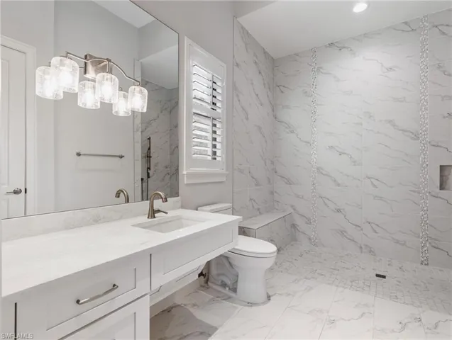 Bathroom featuring a marble finish shower, vanity, and light marble finish flooring