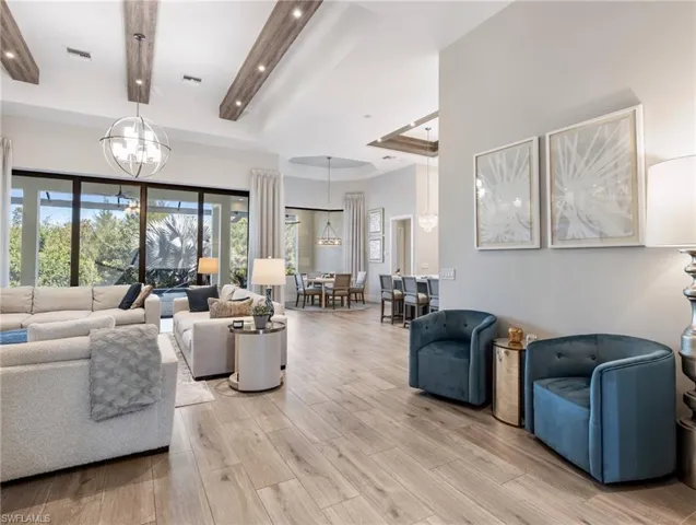 Living area with a tray ceiling, light wood-style flooring, a chandelier, and recessed lighting