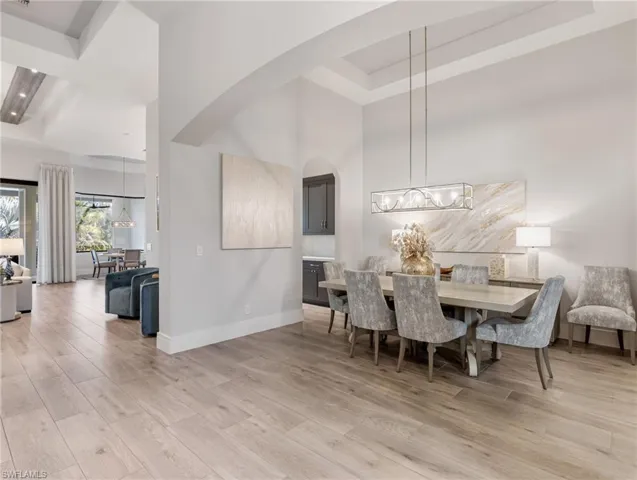 Dining space featuring light wood finished floors, a high ceiling, and a tray ceiling